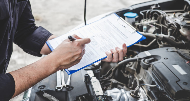 Services car engine machine concept, Automobile mechanic repairman checking a car engine with inspecting writing to the clipboard the checklist for repair machine, car service and maintenance